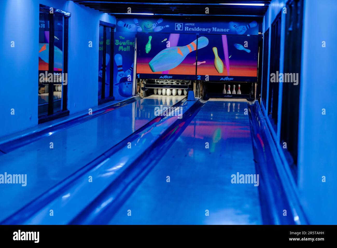Eine Gruppe von Leuten spielt ein virtuelles Bowling-Spiel auf einem großen Flachbildschirm Stockfoto