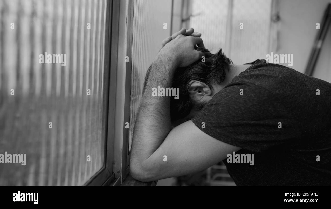 Ein Mann, der zu Hause mit Depressionen kämpft. Dramatische monochromatische schwarz-weiße männliche Person, die an einer psychischen Erkrankung leidet Stockfoto