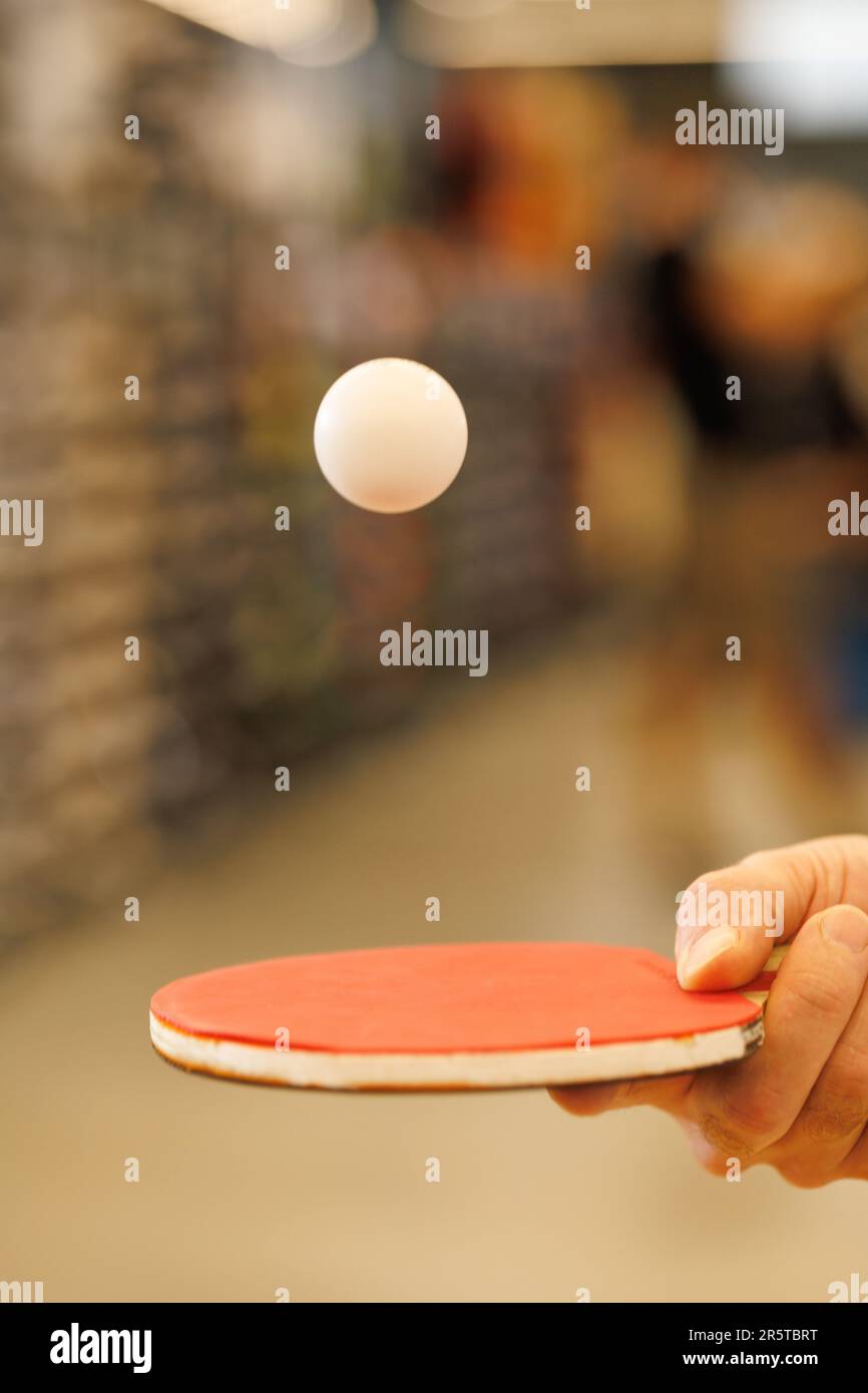 Ein Ball im Flug über einem Tischtennisschläger in der Hand des Spielers Stockfoto