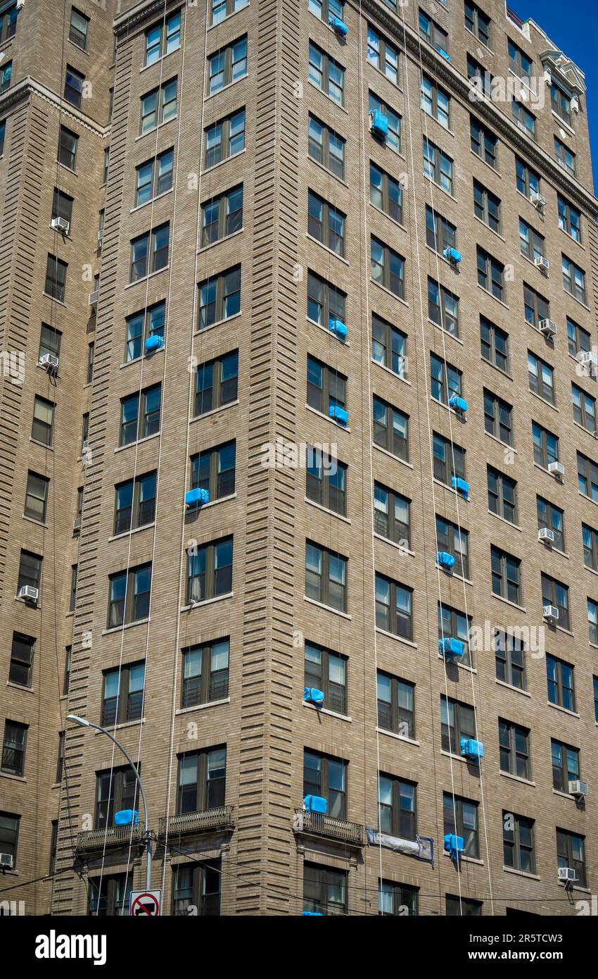 Fensterklimaanlagen, bedeckt mit blauer Schutzplane, sprießen aus Fenstern in einem Gebäude in New York am Donnerstag, 1. Juni 2023. © Richard B. Levine) Stockfoto