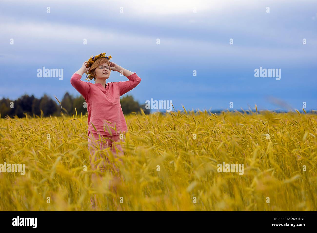 Ukrainische Frau mit einem Kranz auf dem Kopf in einem Weizenfeld, Symbol der ukrainischen Flagge Stockfoto