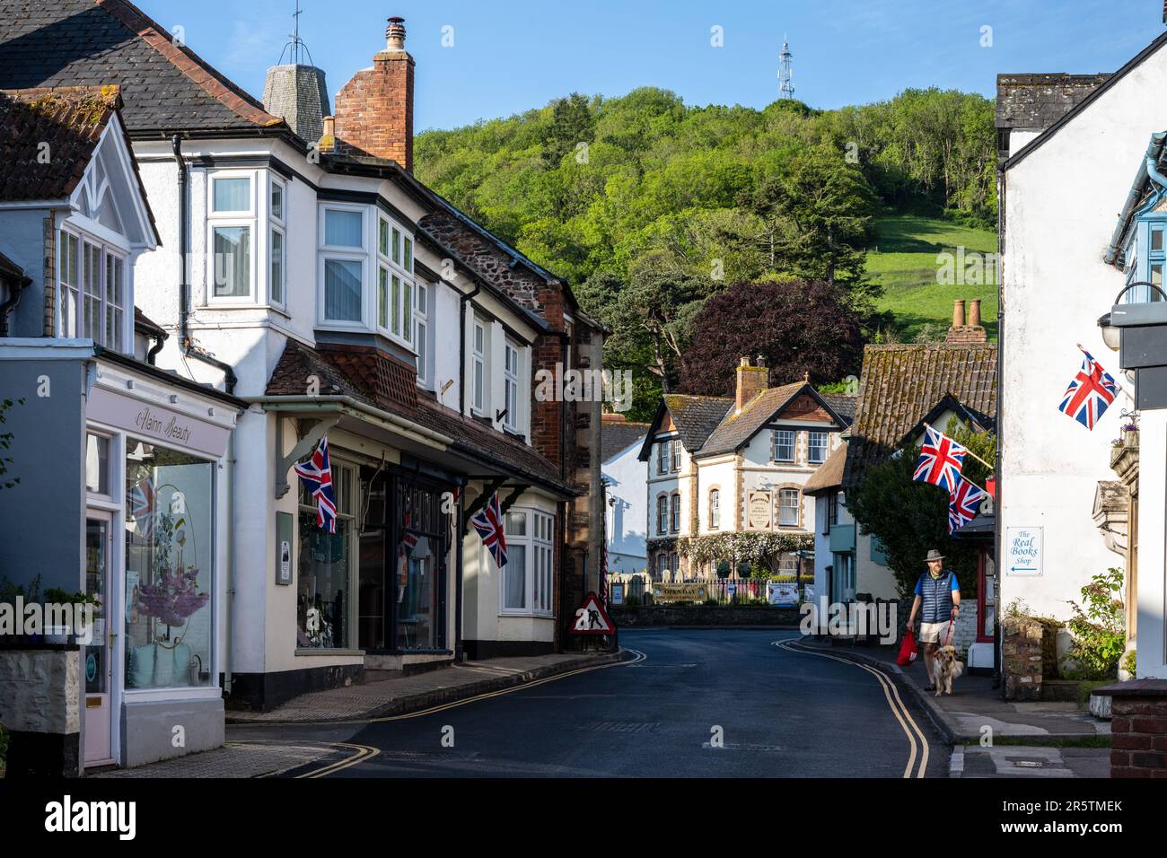 Morgenlicht fällt auf die traditionellen Geschäfte und Häuser der Porlock High Street unter den Hügeln von Exmoor in West Somerset. Stockfoto