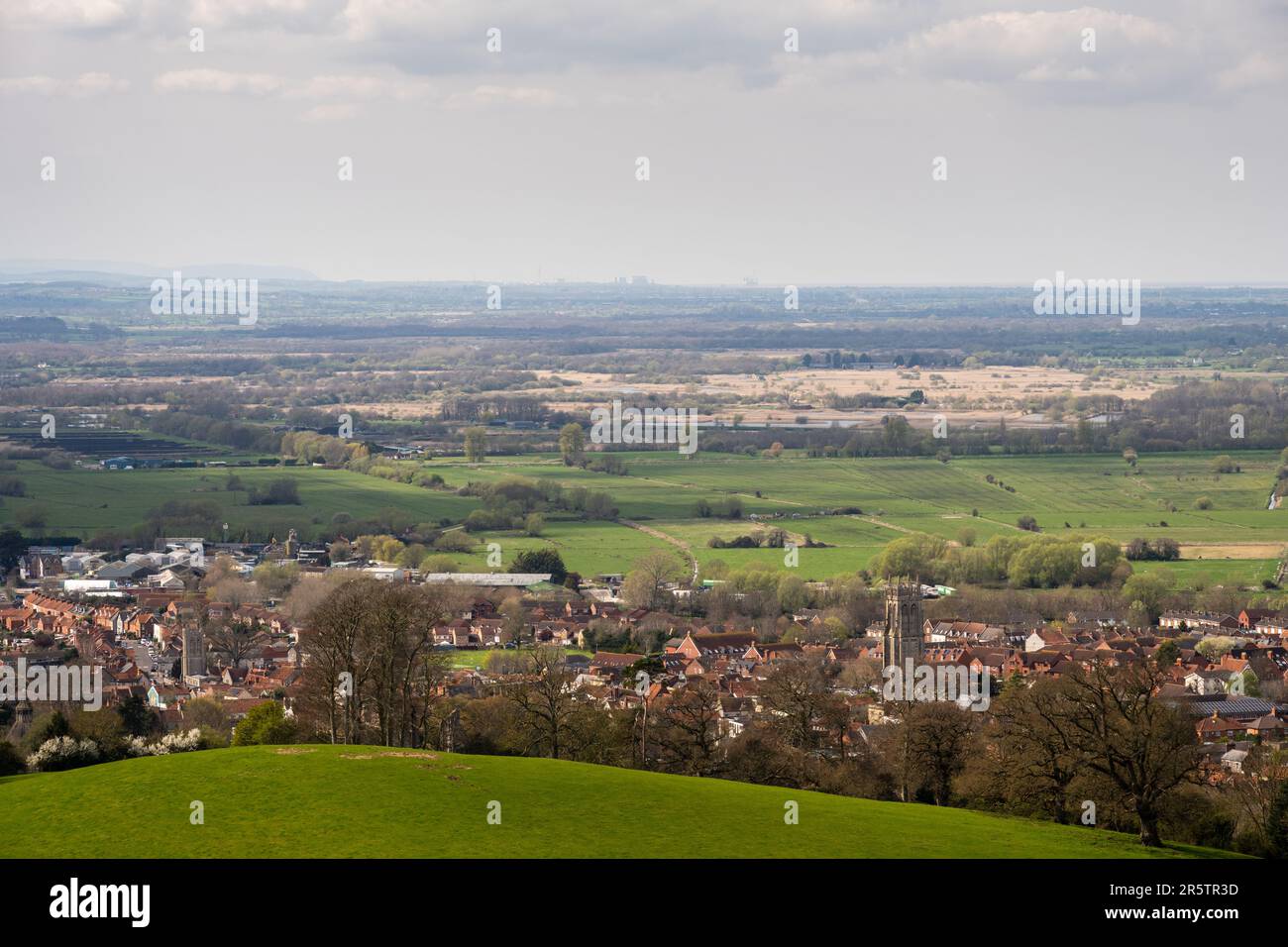 Der Blick über Glastonbury Stadt und die niedrige Feuchtlandschaft der Somerset Ebenen bis zu den entfernten Hinkley Point Kraftwerken von Glastonbury Tor Stockfoto