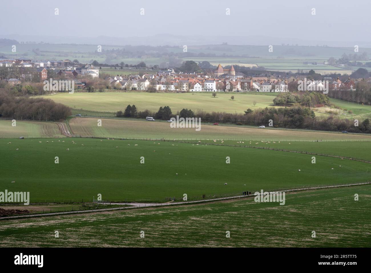 Schafe grasen auf Feldern unterhalb von Maiden Castle in Dorset, mit der neuen Stadt Poundbury dahinter. Stockfoto