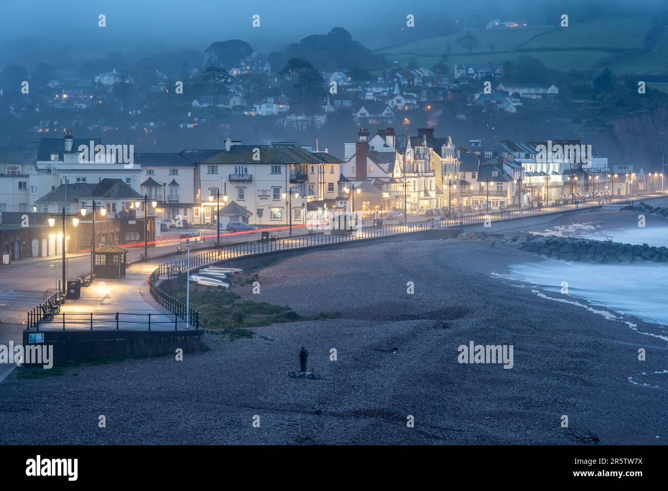 Die Uferpromenade wird in der Abenddämmerung in der Küstenstadt Sidmouth an der Jurassic Coast von Devon beleuchtet. Stockfoto