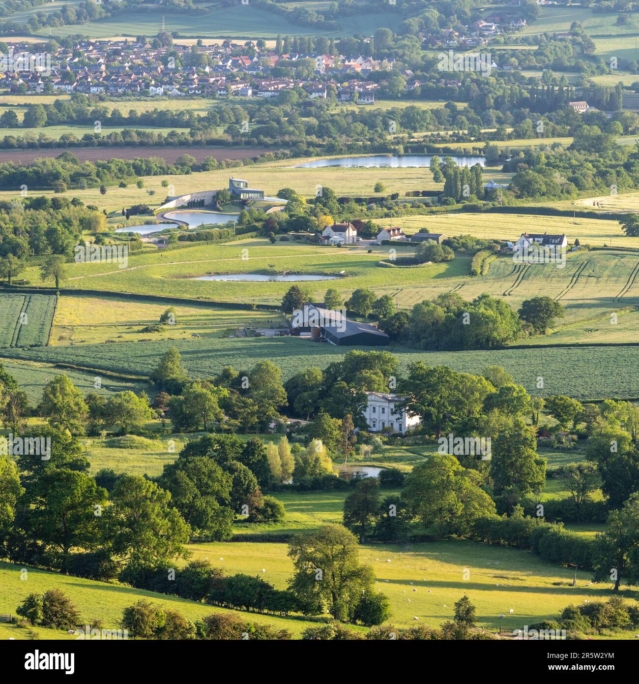 Felder und große Häuser, darunter das modernistische Swinhay House, füllen die Landschaft des ländlichen Gloucestershire unterhalb des Cotswolds Edge bei Wotton-under-E Stockfoto