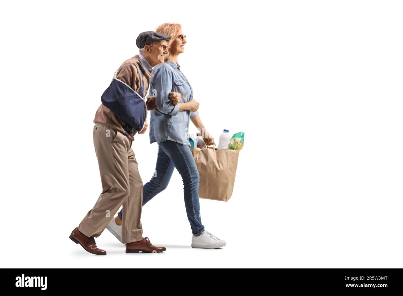 Profilaufnahme über die gesamte Länge einer Frau, die einem älteren Mann mit einem verletzten Arm hilft und Einkaufstüten auf weißem Hintergrund trägt Stockfoto