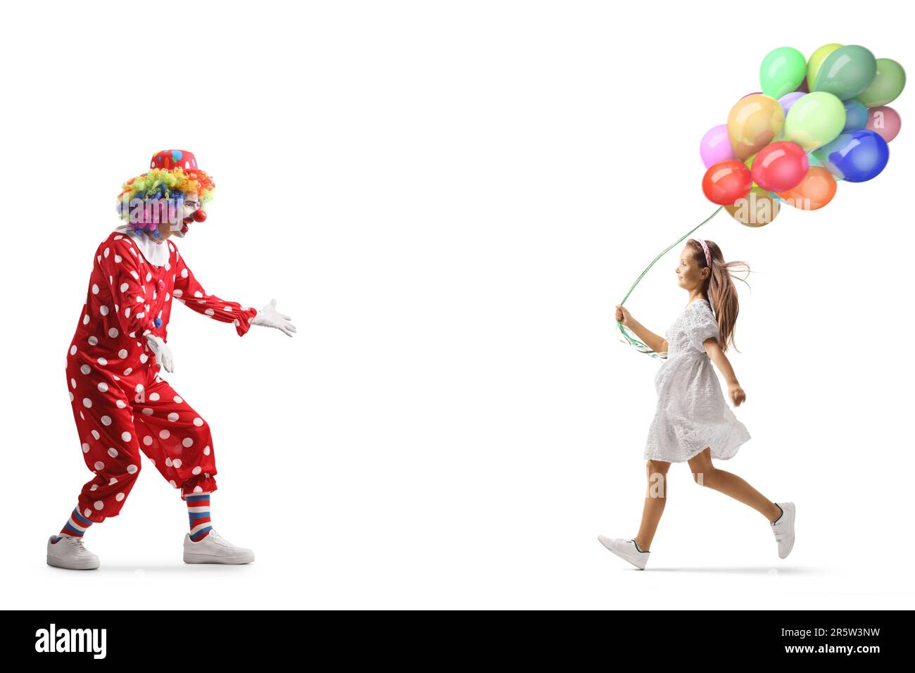 Ein Mädchen hält Ballons und rennt auf einen Clown zu, isoliert auf weißem Hintergrund Stockfoto