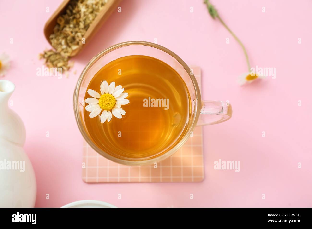 Teekanne und Tasse heißer Kamillentee auf pinkfarbenem Hintergrund Stockfoto
