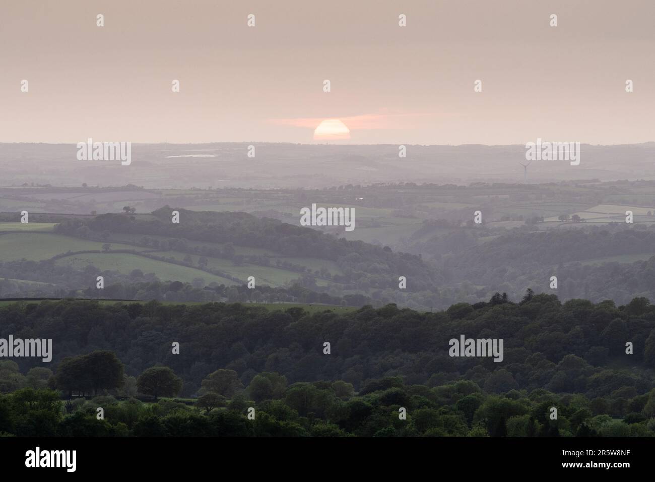 Die Sonne geht über den Lyd- und Tamar-Tälern und den Hügeln von Cornwall unter, wie sie von Brent Tor in West Devon aus zu sehen ist. Stockfoto