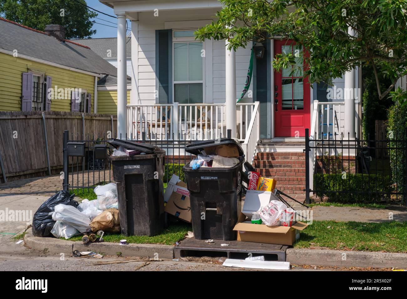 NEW ORLEANS, LA, USA - 22. MAI 2023: Müll stapelte sich auf dem Bordstein und überlaufende Müllwagen vor dem Haus in der Universitätsgegend Stockfoto
