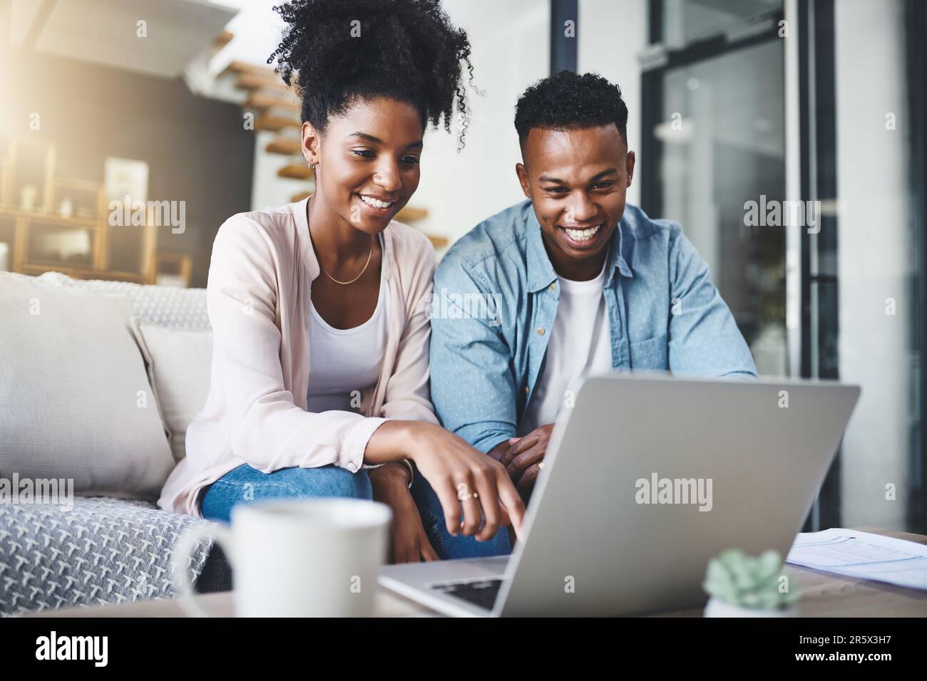 Alles, was sie brauchen, ist im Netz. Ein glückliches junges Paar, das zu Hause einen Laptop zusammen auf dem Sofa benutzt. Stockfoto