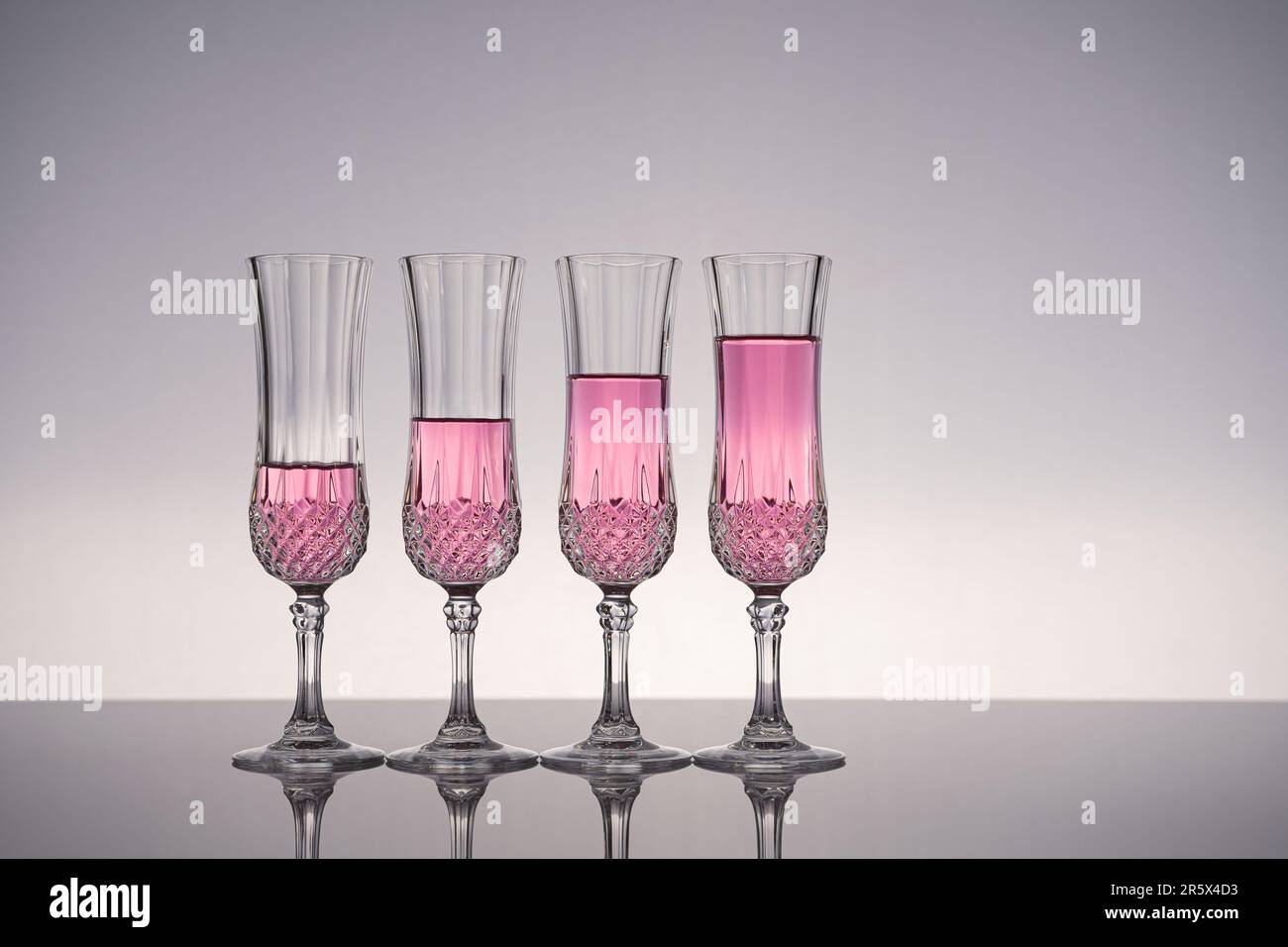 Sektglas, Sektflöte, isoliert auf glänzend grauer Oberfläche mit grauem Hintergrund. Stockfoto