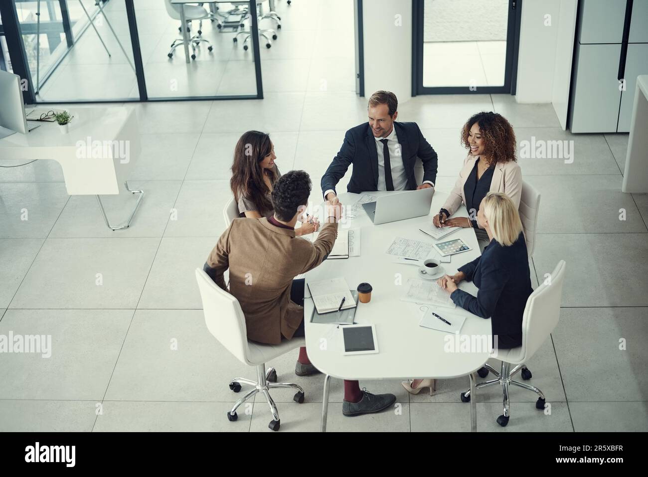 Treffen, begrüßen und umsetzen. Zwei Geschäftsleute, die sich während eines Meetings in einem modernen Büro die Hand schütteln. Stockfoto