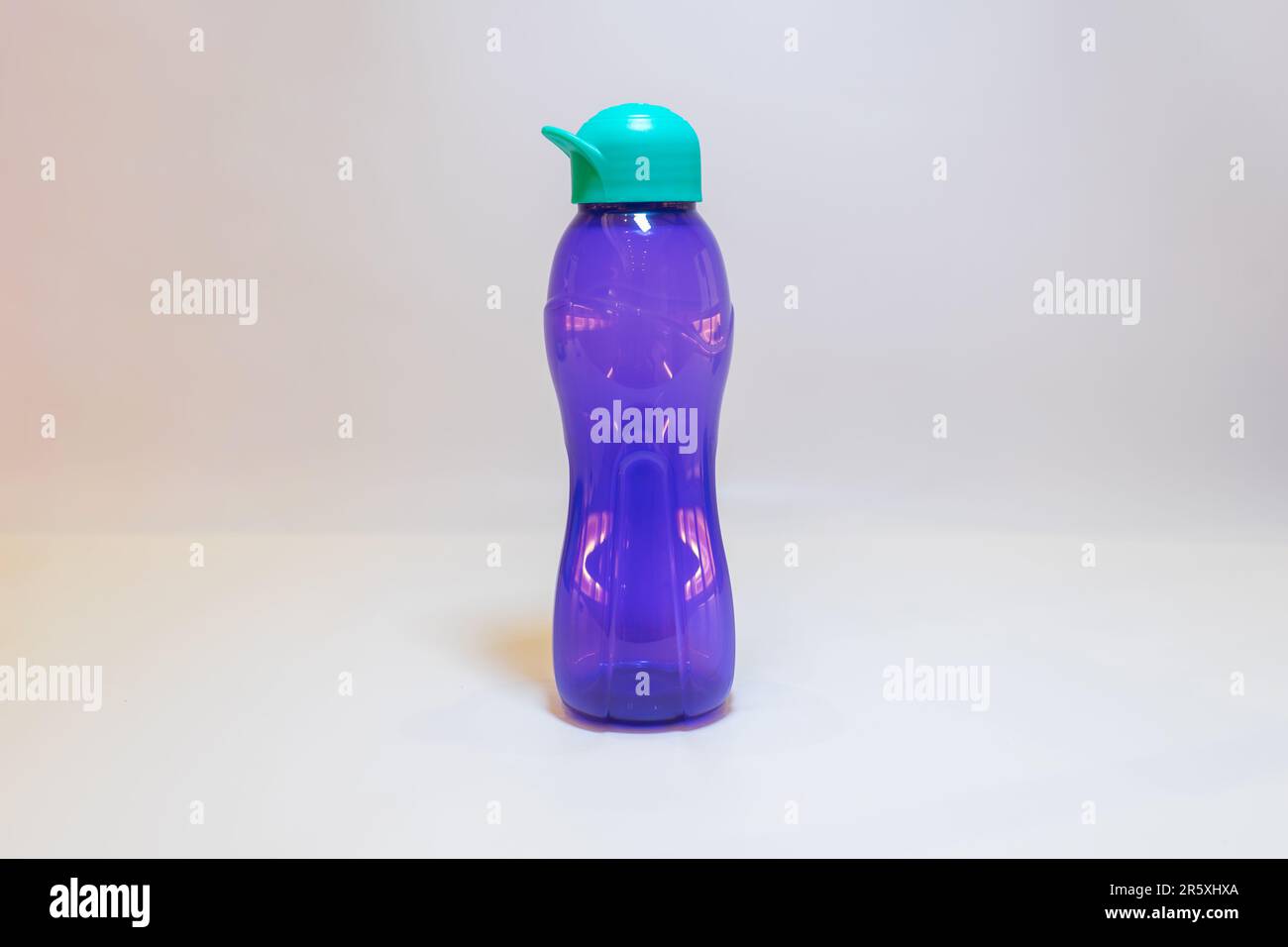 Die lila Wasserflasche mit blaugrünem Deckel ist der perfekte Begleiter, um den ganzen Tag über ausreichend Flüssigkeit zu tanken. Stockfoto