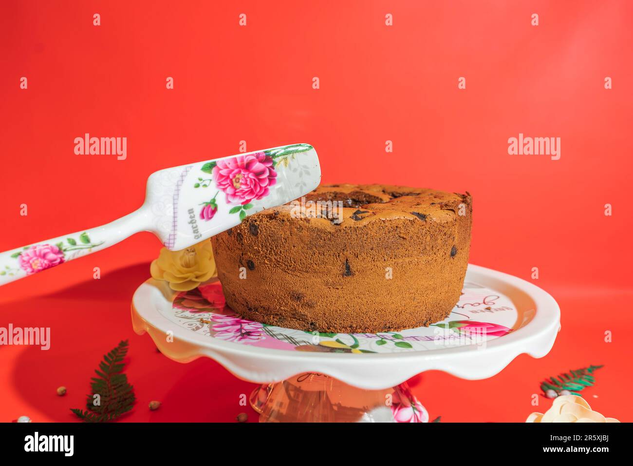 Der runde Kuchenstand aus weißem Keramik mit Blumenmotiv ist ein atemberaubendes Herzstück für Ihre Desserts. Stockfoto