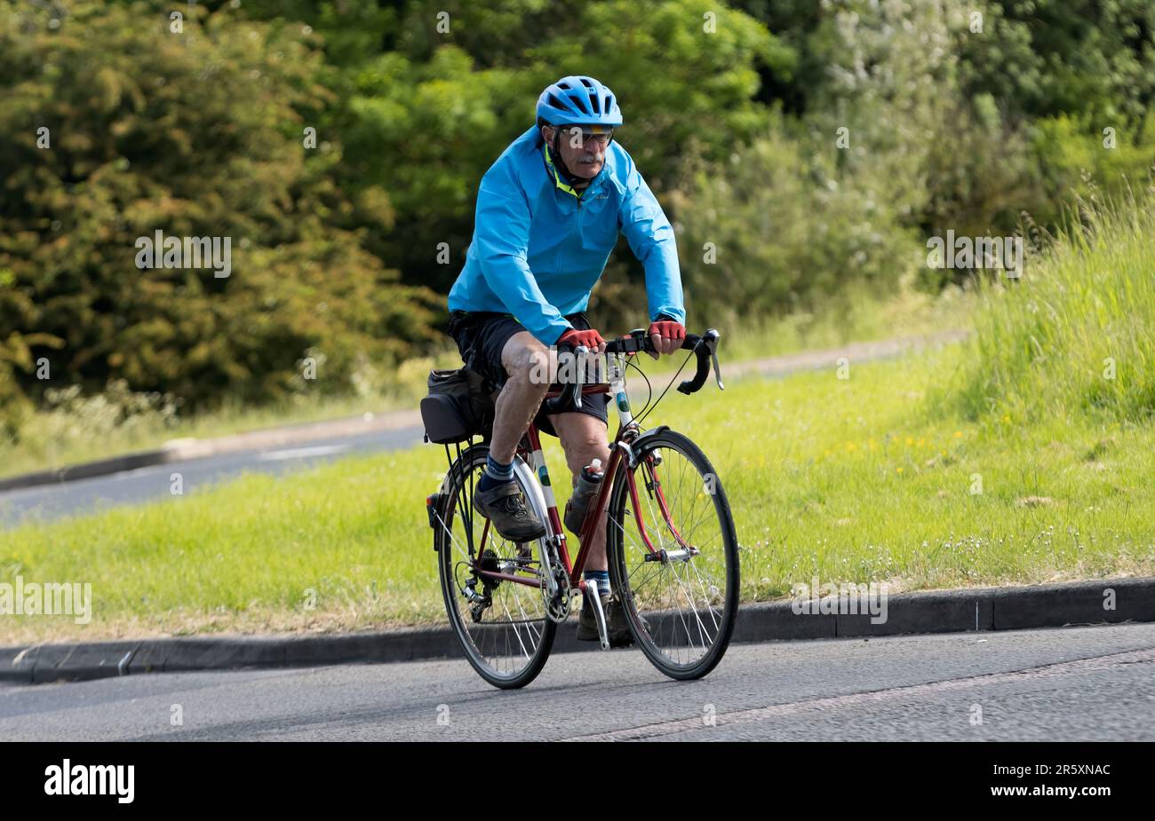 Stony Stratford, Großbritannien - Juni 4. 2023: Älterer Mann fährt Fahrrad auf einer englischen Landstraße. Stockfoto