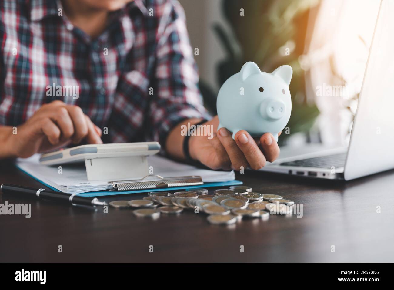 Eine Geschäftsfrau, die ein blaues Sparschwein hält, um Ausgaben zu berechnen, Geld zu sparen, Vermögen und Finanzkonzept, Finanzen, Investitionen, Finanzplanni Stockfoto