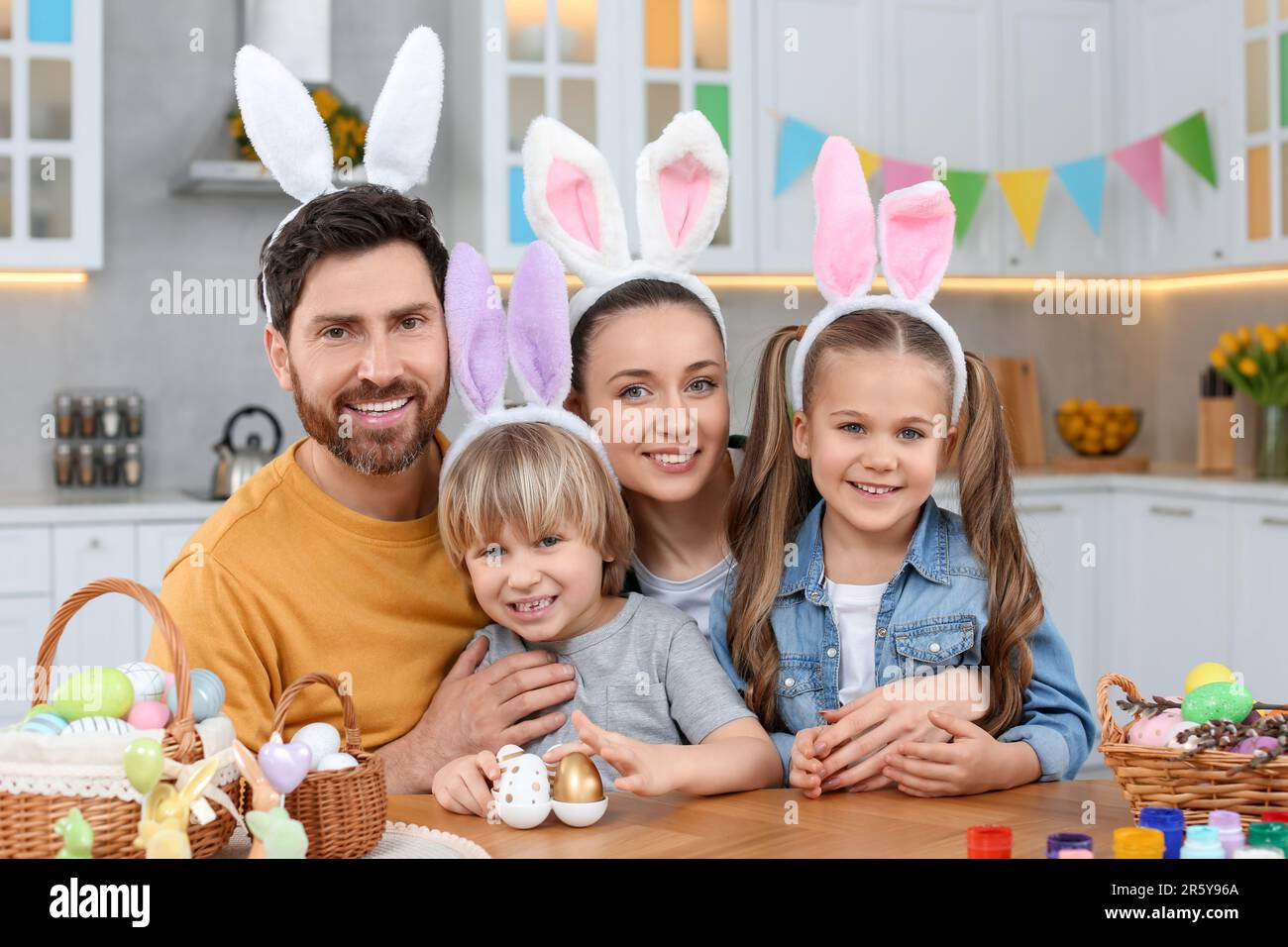 Glückliche Familie mit Ostereiern am Tisch in der Küche Stockfoto