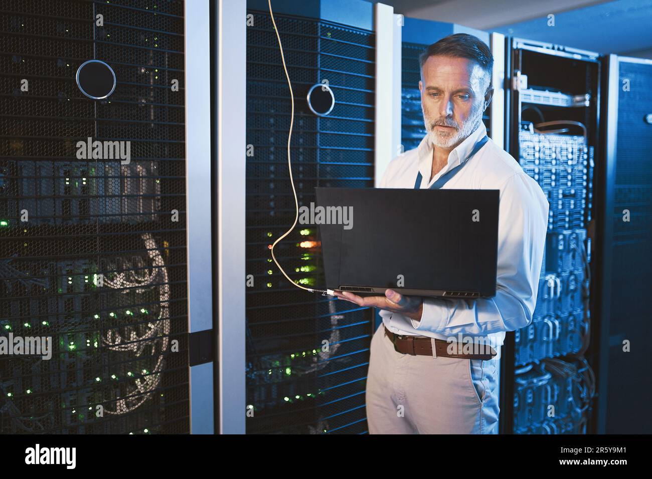 Alles unter Kontrolle und immer in Verbindung halten. Ein erwachsener Mann, der ein Notebook verwendet, während er in einem Serverraum arbeitet. Stockfoto