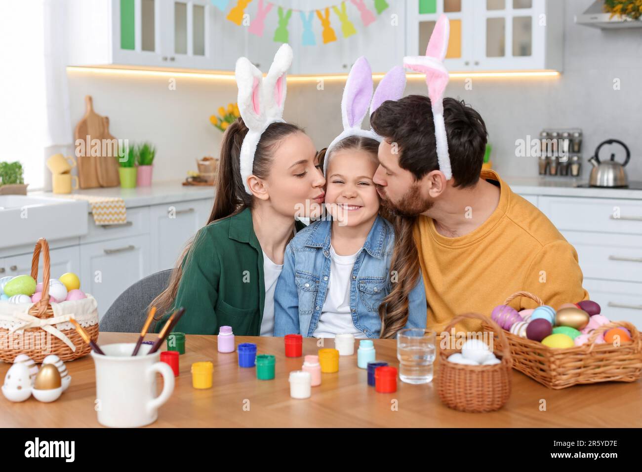 Glückliche Familie mit Ostereiern am Tisch in der Küche Stockfoto