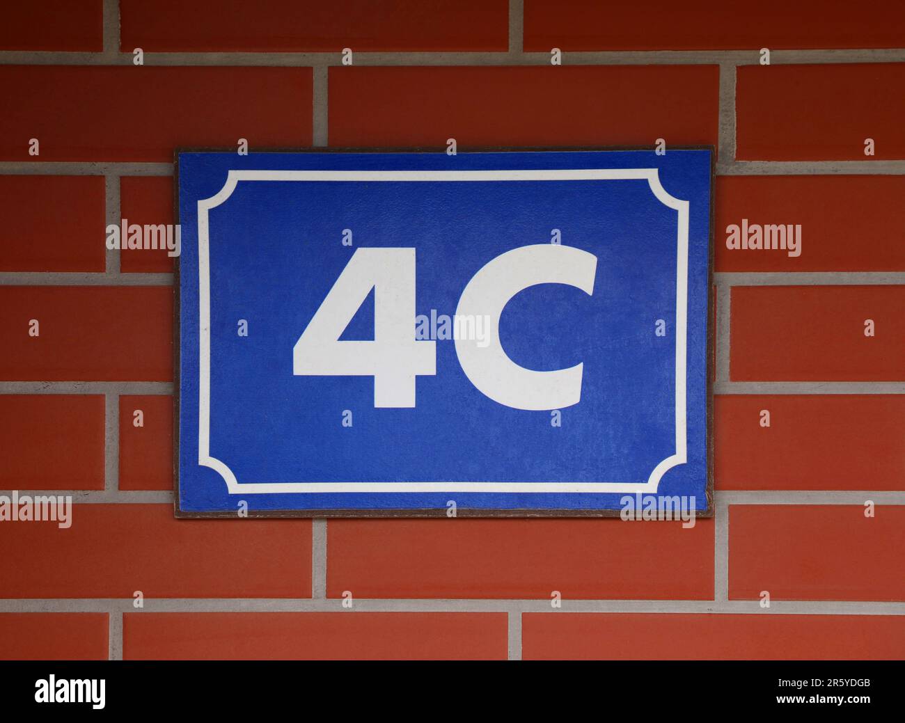 Schild mit Hausnummer 4 an der Ziegelwand Stockfoto