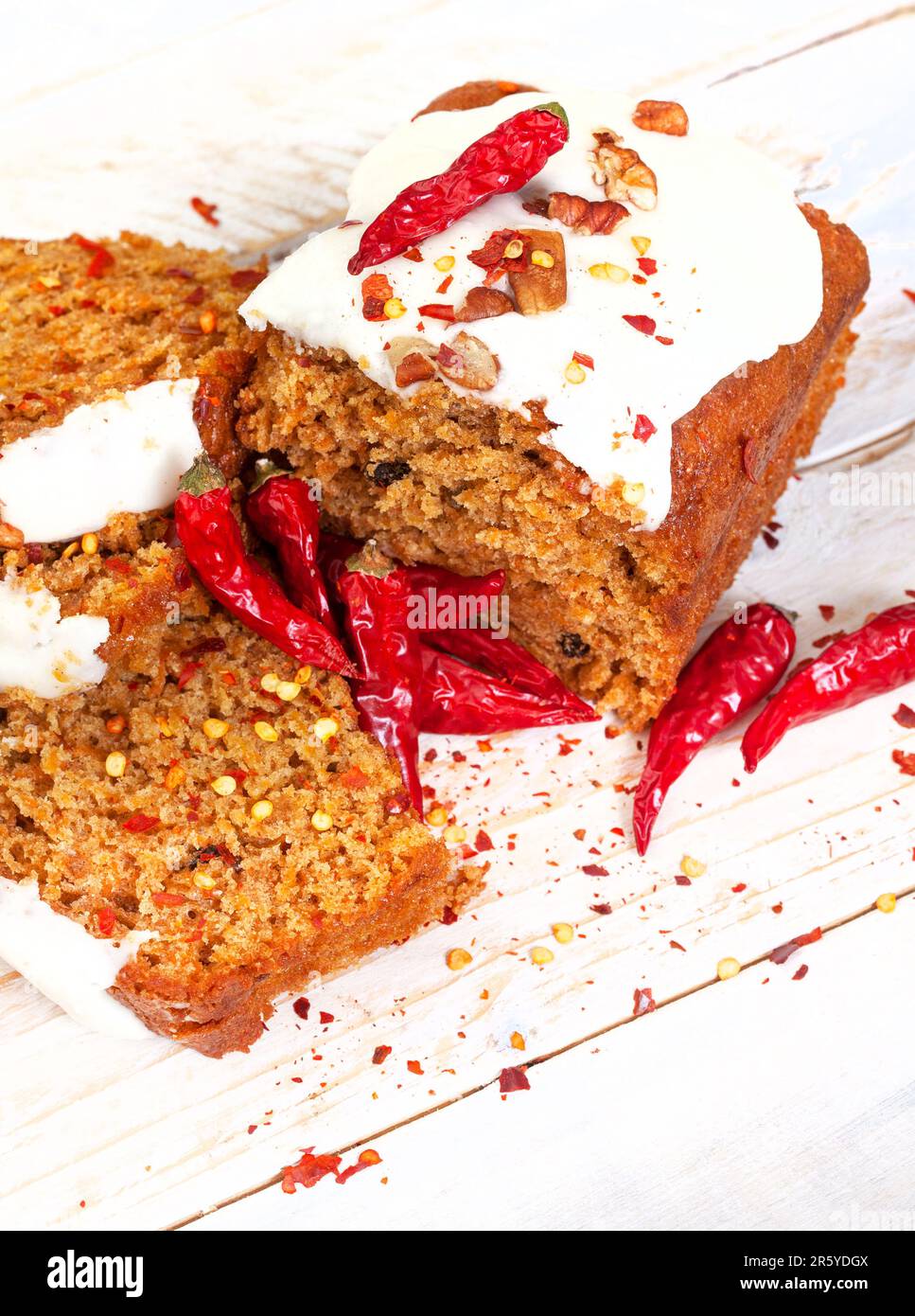 Wütender Karottenkuchen, Karottenkuchen mit Chiliflocken. Dekadente süße und würzige Leckerei. In Scheiben mit Chili auf weißem Holz Stockfoto