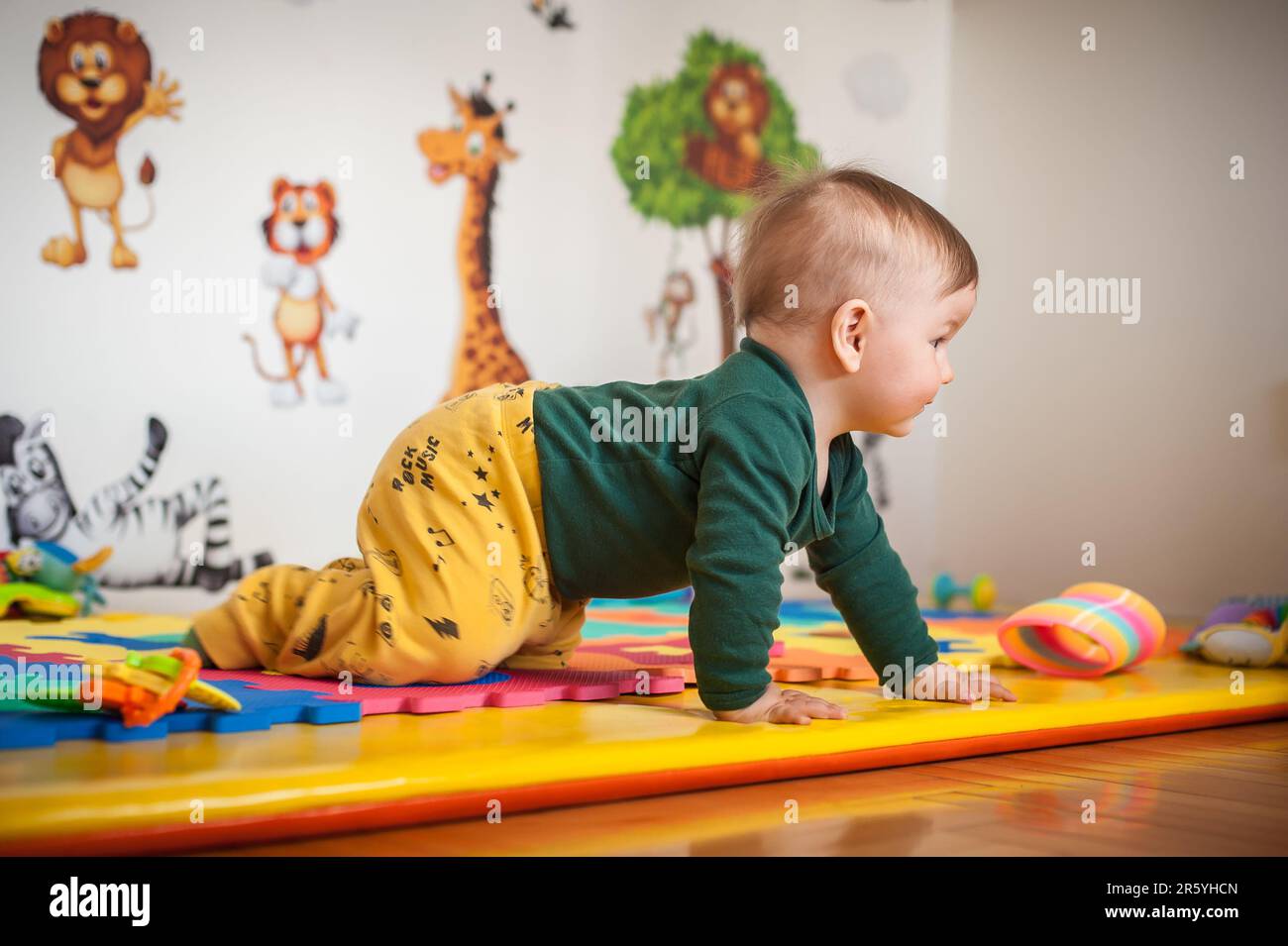 Der süße Junge krabbelt auf dem Hausboden herum, erkundet die Welt und lernt, sich zu bewegen. Seitenansicht. Liebe und Familiengefühle Stockfoto