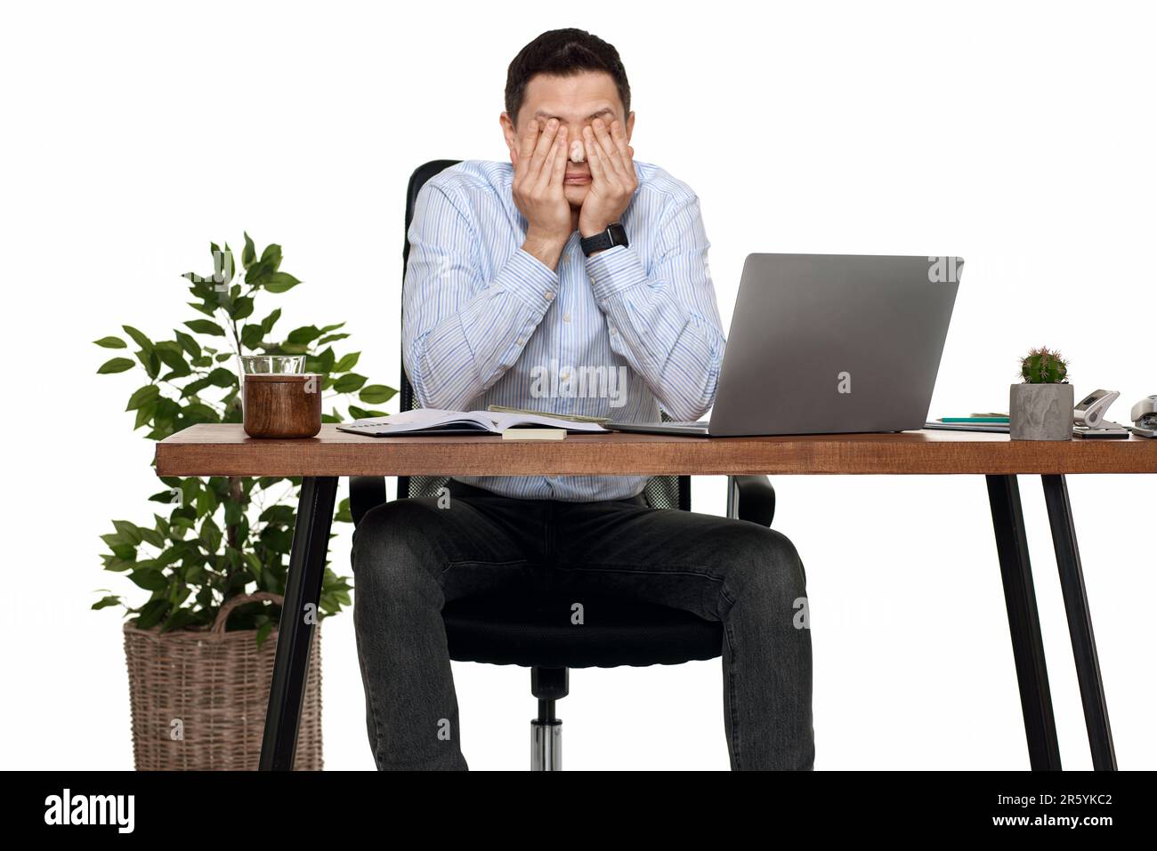 Ein Mann hat Kopfschmerzen, wenn er im Büro ein Notebook benutzt Stockfoto