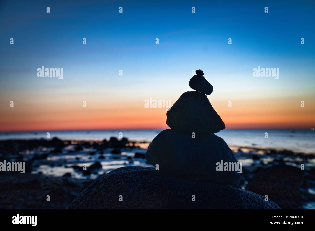 Steinpyramide an der Ostsee mit Blick auf das Meer bei Sonnenuntergang und Blue Hour. Steine als Silhouette. Spirituelle Sichtweise. Landschaftsaufnahmen von Poel Island Stockfoto