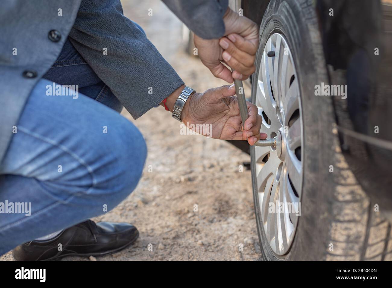 Detail eines Latino-Mannes, der eine Mutter lockert, um einen Platten Reifen zu wechseln. Stockfoto