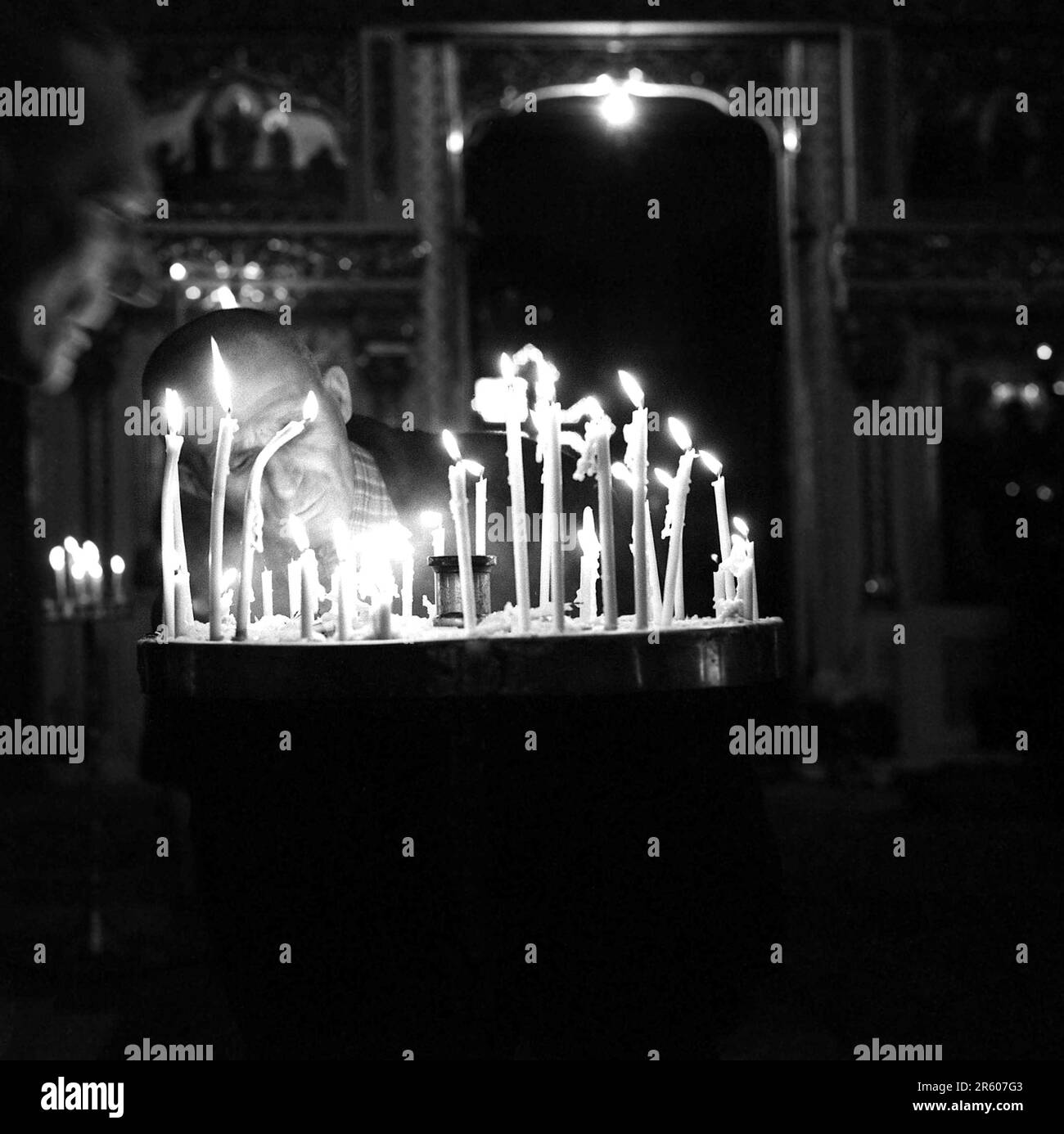 Rumänien, ca. 1980. Ein Mann in einer christlich-orthodoxen Kirche betet und verbrennt traditionell eine Kerze. Stockfoto