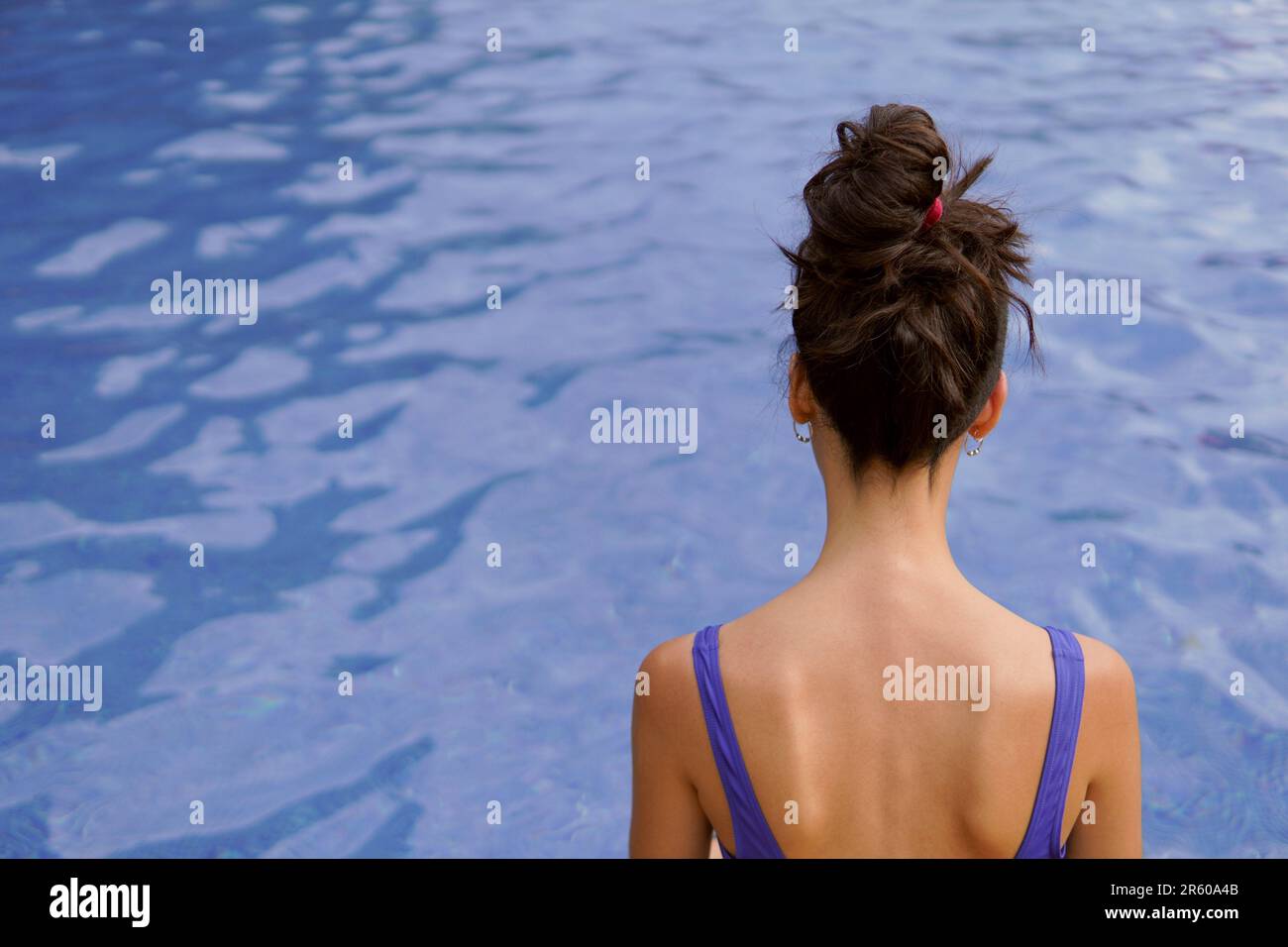 Eine schlanke Frau, die in den Sommerferien in einem Swimmingpool sitzt Stockfoto