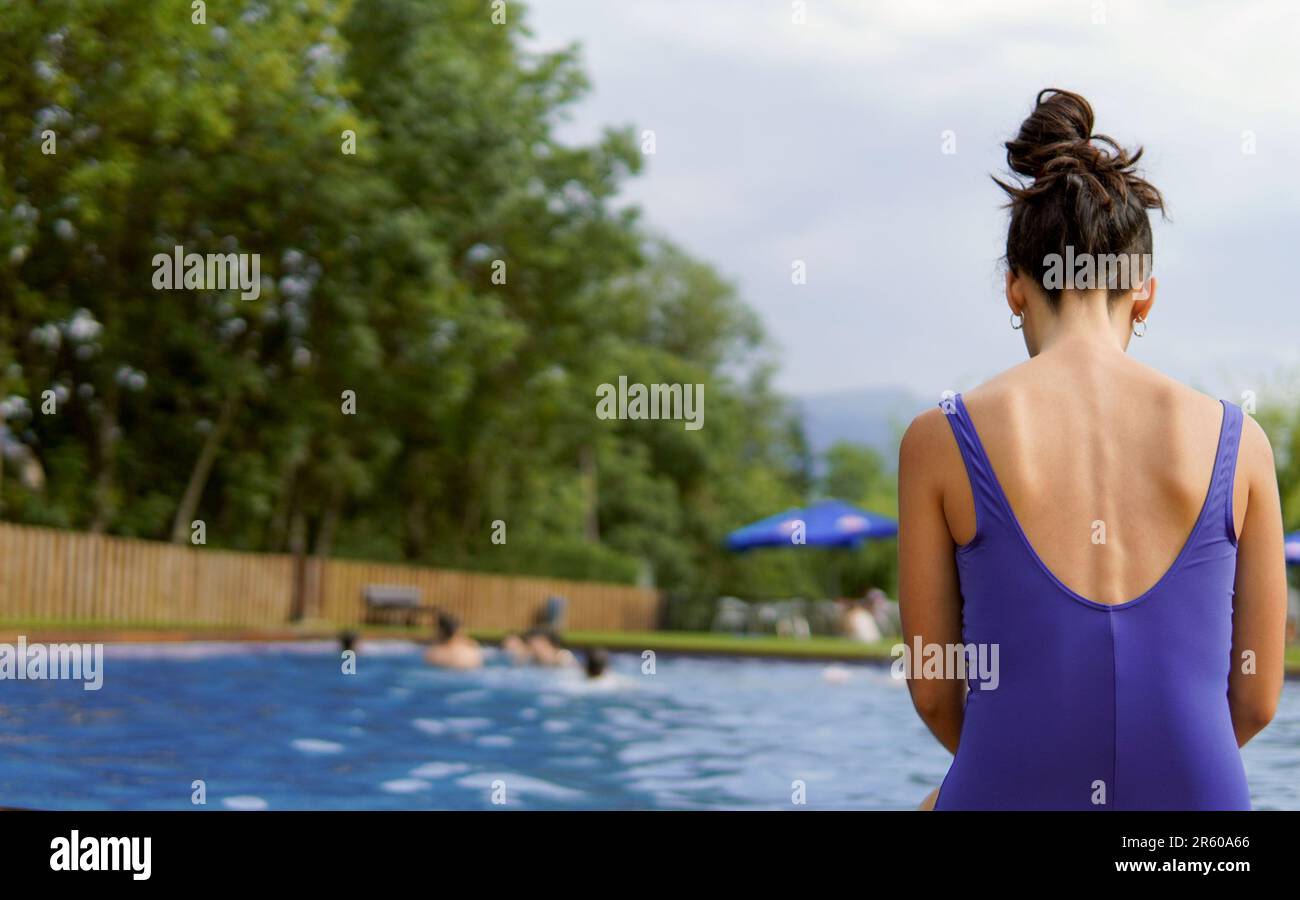 Ein schlanker Körper einer psychisch kranken Frau, die im Sommerurlaub im Schwimmbad sitzt Stockfoto