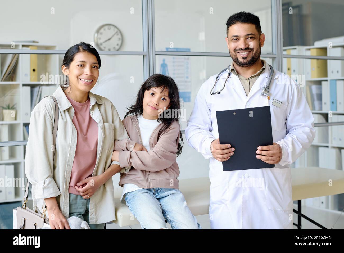 Porträt einer mutter mit einem Kind, das vor der Kamera lächelt, zusammen mit einem Kinderarzt in der Praxis Stockfoto