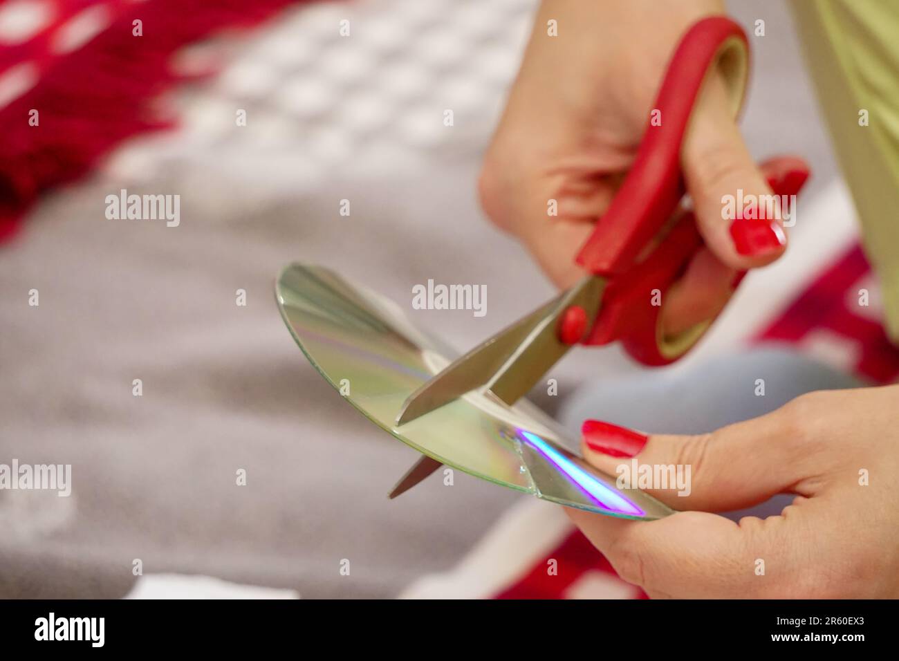 Frau schneidet alte CDs mit einer Schere zu Hause aus nächster Nähe Stockfoto