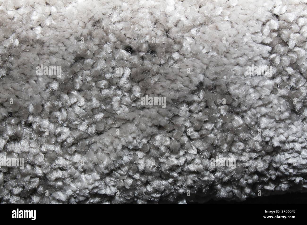 Nahaufnahmetextur eines weichen grauen Teppichs mit weicher, samtiger Oberfläche. Das Bild erfasst die feinen Details der Fasern und zeigt die Wärme des Materials Stockfoto