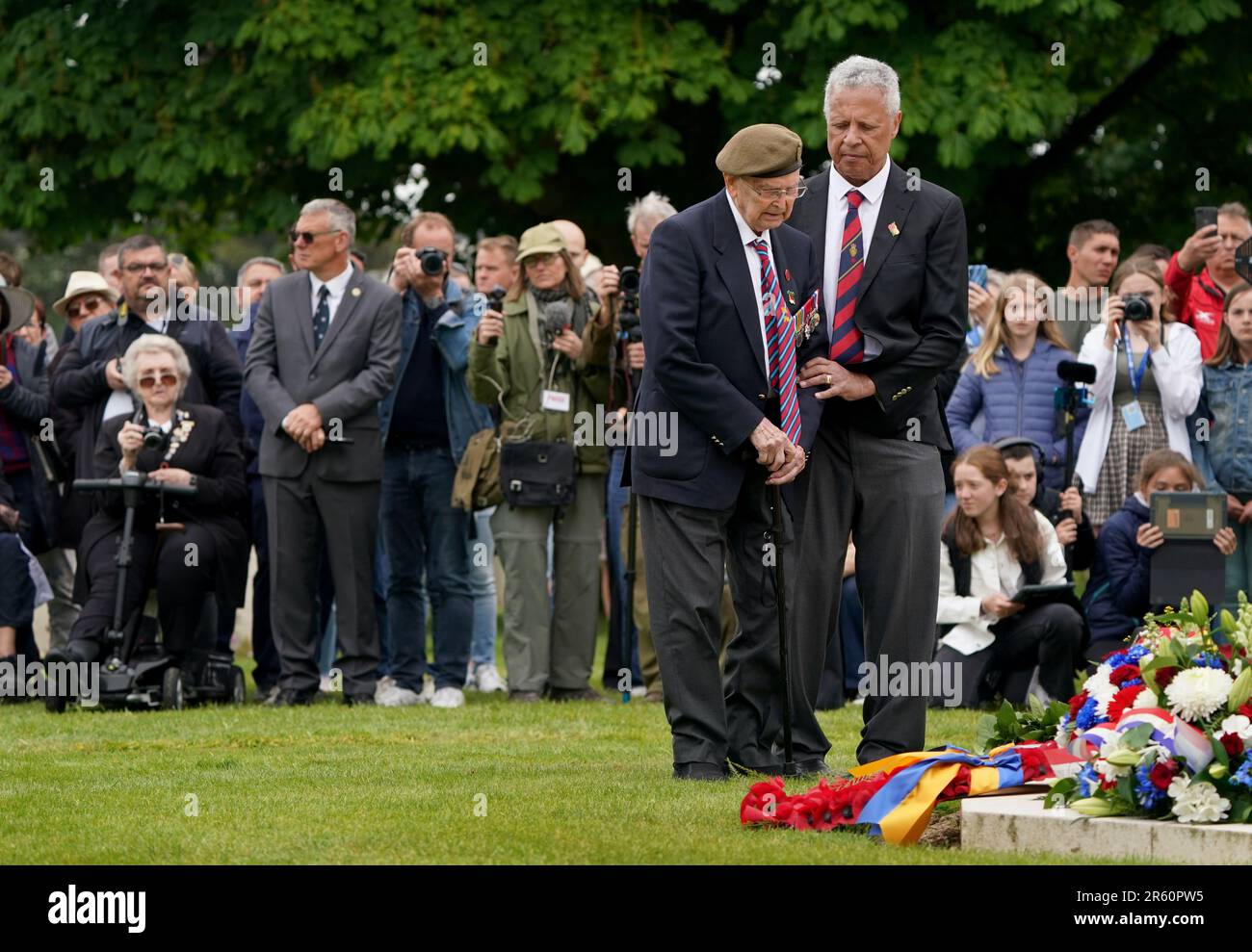 Der D-Day-Veteran Reg Pye (links) wird beim Royal British Legion (RBL) Service of Remembrance anlässlich des 79. Jahrestages der D-Day-Landungen auf dem Bayeux-Friedhof in der Normandie, Frankreich, beim Verlegen eines Kranzes unterstützt. Der Dienst erinnert an die 22.442 Soldaten und Frauen aus 38 verschiedenen Ländern, die am D-Day und während der Schlacht in der Normandie im Sommer 1944 unter britischem Kommando starben. Foto: Dienstag, 6. Juni 2023. Stockfoto