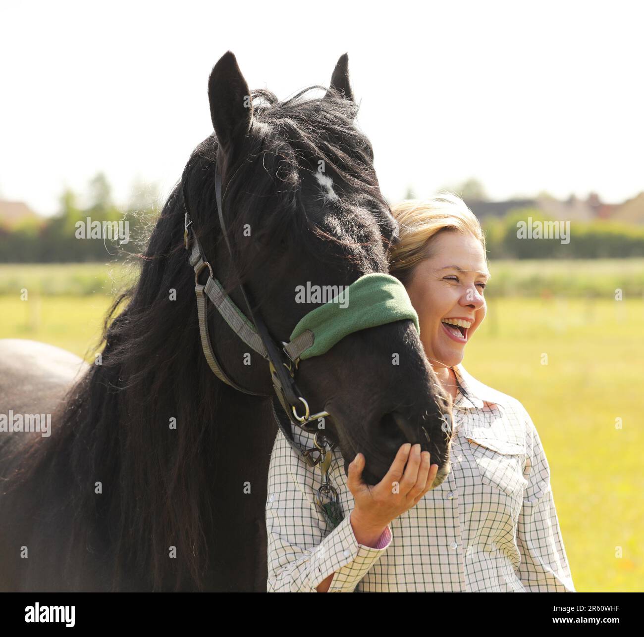 Eine blonde Frau, die ein schwarzes Pony umarmt Stockfoto