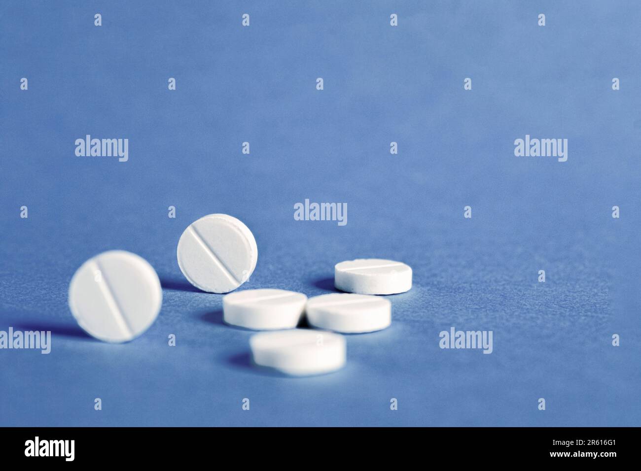 Weiße runde medizinische Pillen auf blauem Hintergrund. Medizinisches und pharmazeutisches Behandlungskonzept. Speicherplatz kopieren Stockfoto