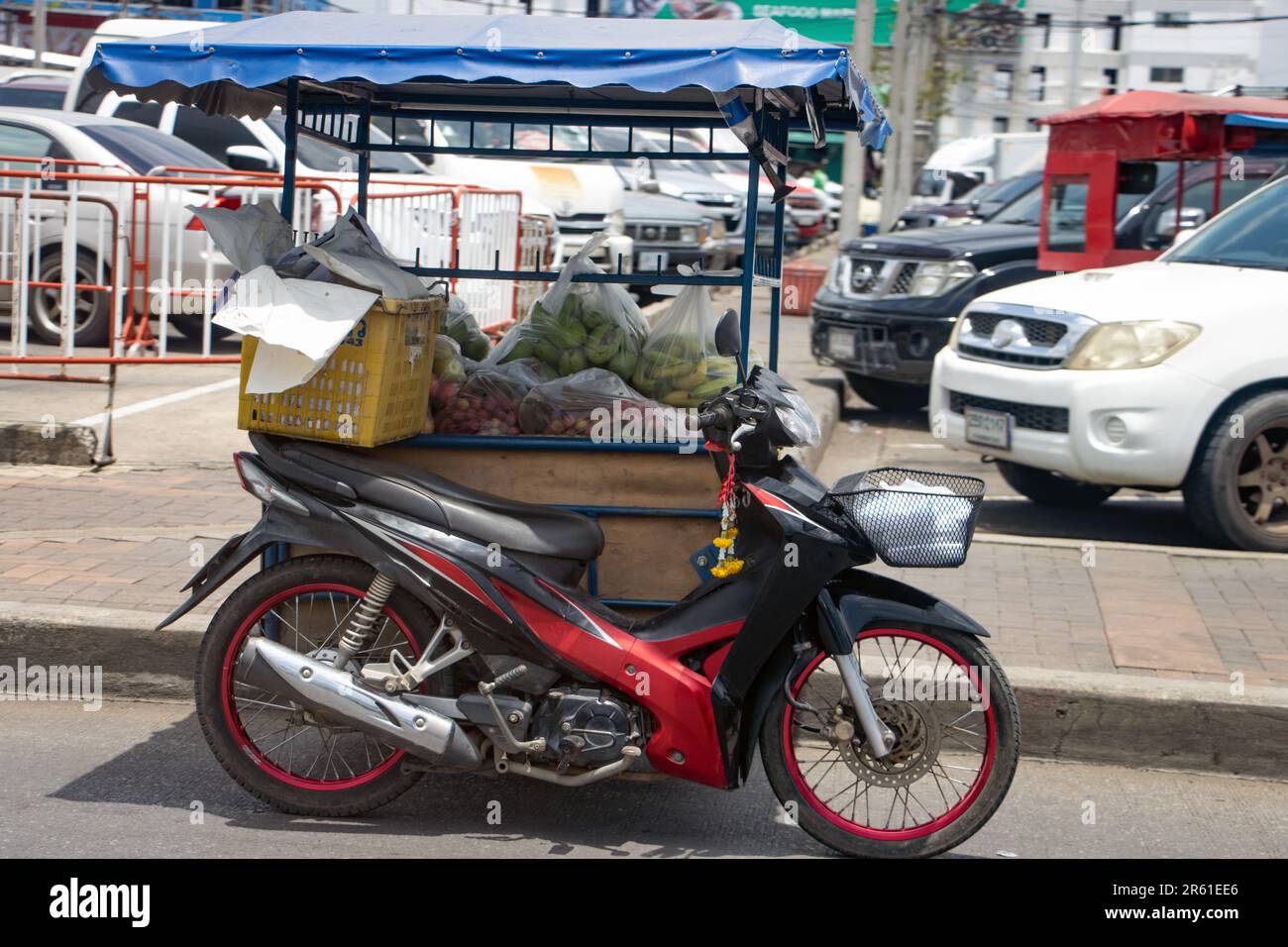 Auf der Straße neben dem Markt in Bangkok, Thailand, steht ein Motorrad mit Beiwagen, beladen mit Taschen mit frischem Obst Stockfoto