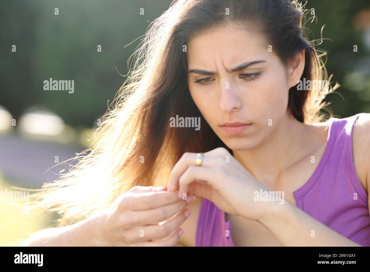 Besorgte Verlobte, die sich den Verlobungsring in einem Park ansieht Stockfoto