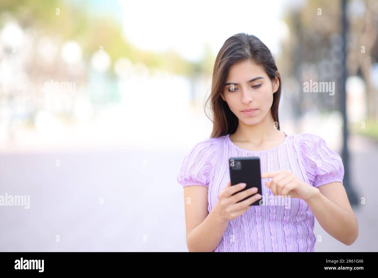 Die Vordertür einer Frau, die auf der Straße mit dem Handy unterwegs ist Stockfoto