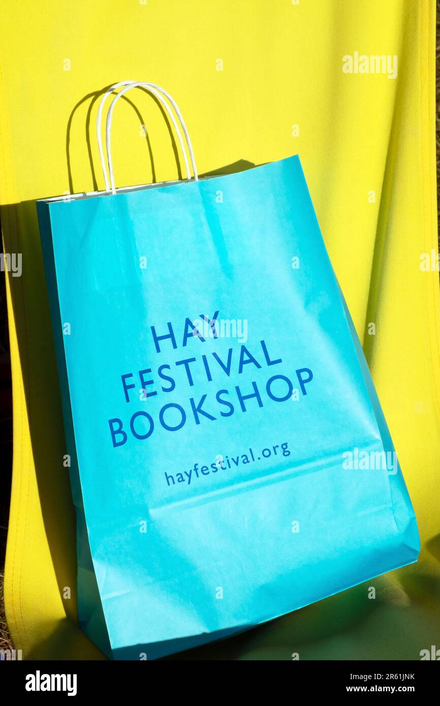 Türkisblaue Tragetasche für den Hay Festival Bookshop auf gelbem Segeltuchboden beim Hay Festival 2023 in Hay-on-Wye Wales UK Stockfoto