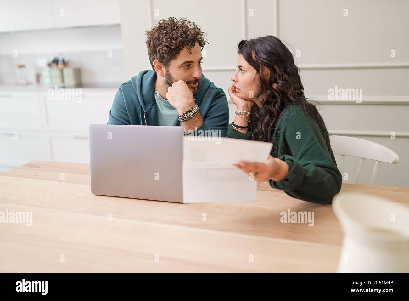 Ein junges Ehepaar, das die Haushaltsfinanzen zusammen verwaltet. Mit einem Laptop vor ihm und einem besorgten Blick auf ihr Gesicht, navigieren sie durch die Galerie Stockfoto