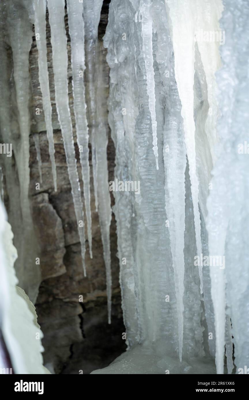 Eine abstrakte Nahaufnahme eines rauschenden Eiswasserfalls mit zahlreichen Eiszapfen an der Seite Stockfoto