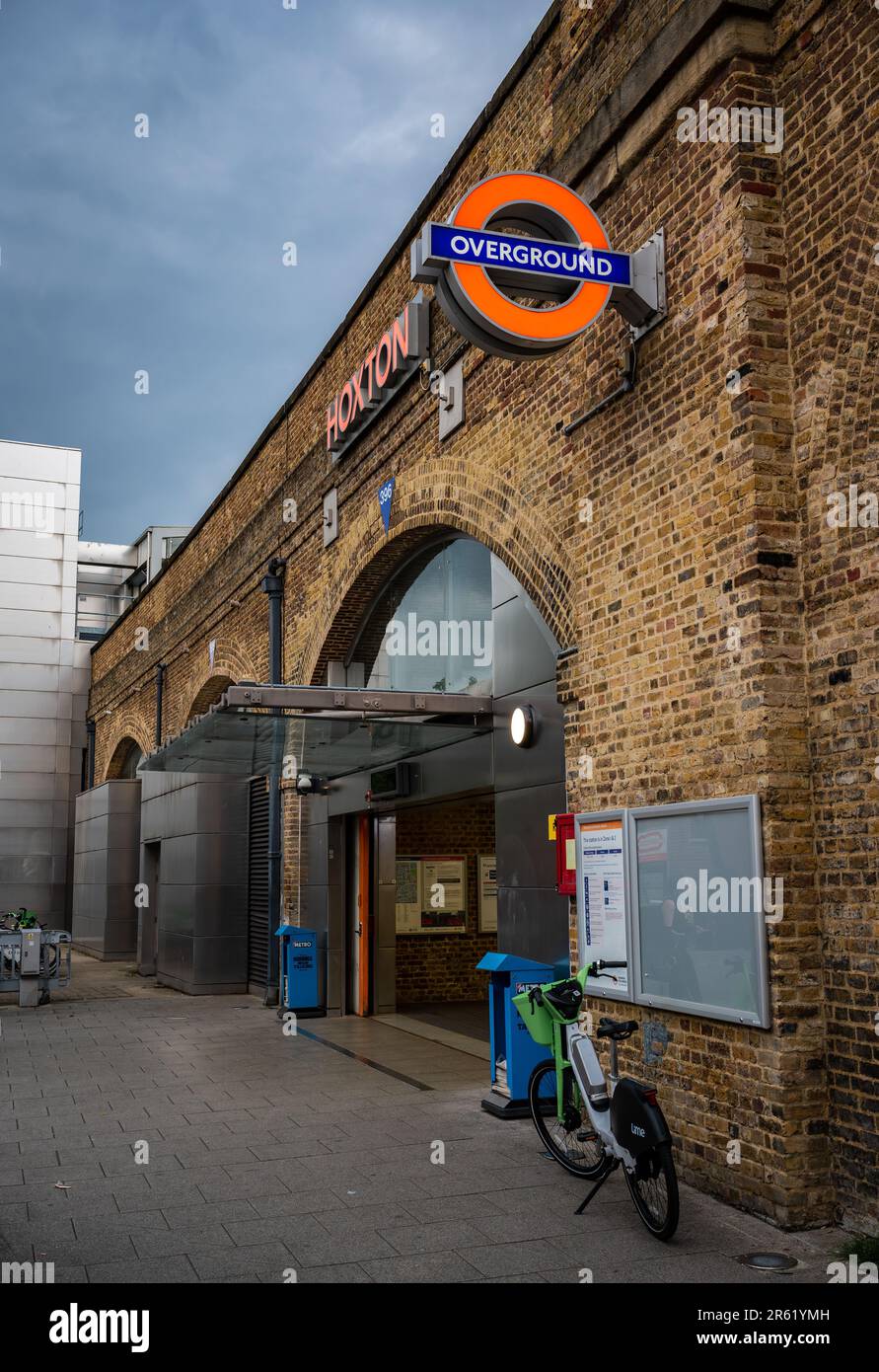 London, Vereinigtes Königreich: Hoxton Station an der Überlandlinie in London. Vor dem Bahnhof befindet sich ein Fahrrad, und über dem Hotel befinden sich dunkle Wolken. Stockfoto
