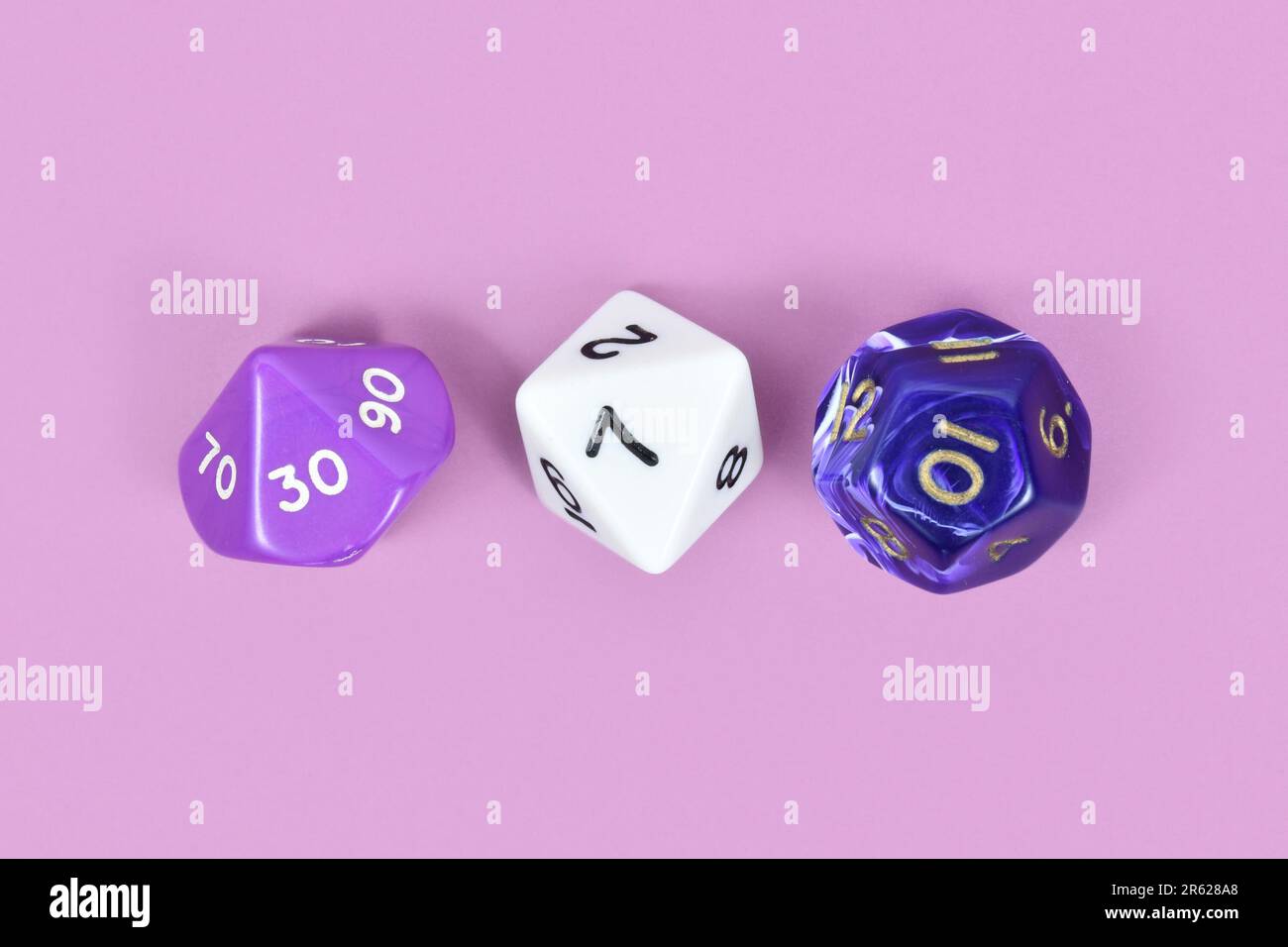 Drei verschiedene Rollenspiel-RPG-Würfel auf violettem Hintergrund Stockfoto