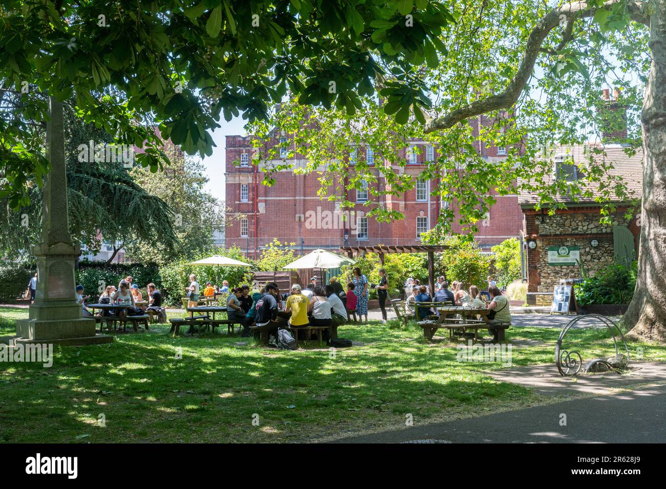 Leute, die an Tischen vor dem Cafe im Park sitzen und an einem sonnigen Sommertag Essen und Getränke genießen, Victoria Park, Portsmouth, Hampshire, England, UK Stockfoto