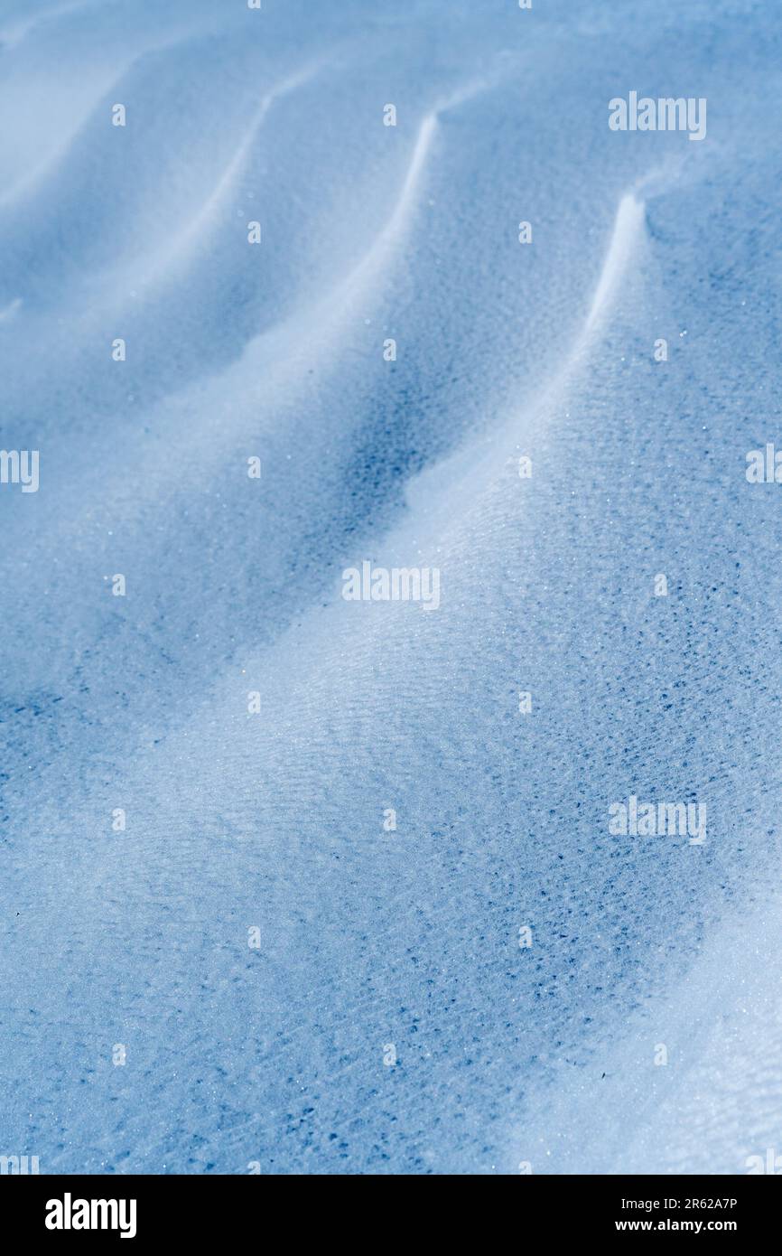 Ein vertikales Foto einer schneebedeckten Landschaft mit einer riesigen Fläche weißer Schneeverwehungen Stockfoto